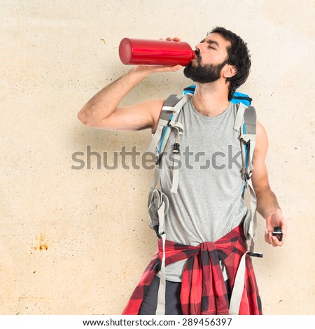 Backpacker drinking water over textured background