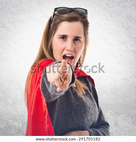 Girl dressed like superhero pointing front over textured background