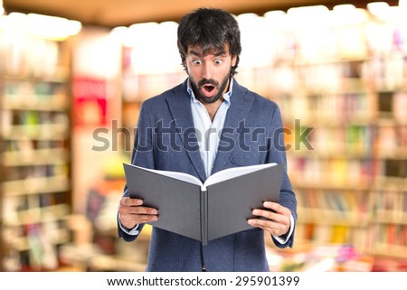 Surprised man reading a book on unfocused background