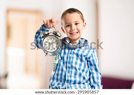 Boy holding an antique clock inside house
