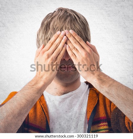 Blonde man covering his eyes over grey background