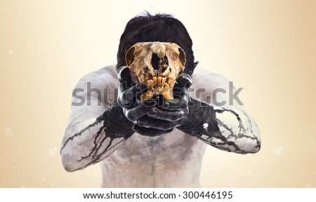 Primitive man offering a rabbit skull over ocher background