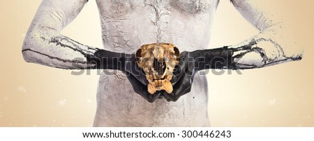 Primitive man holding rabbit skull over ocher background