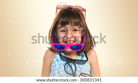Girl wearing many sunglasses over ocher background