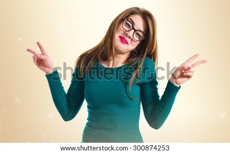 Girl doing victory gesture over ocher background