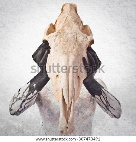 prehistoric man with horse skull over grey background