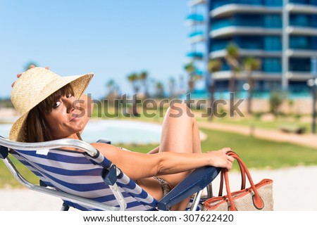 Woman sitting on beach chair on unfocused background