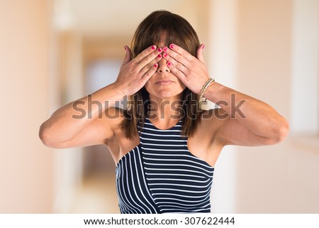 Woman covering her eyes on unfocused background