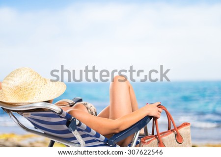 Woman resting on beach chair on unfocused background