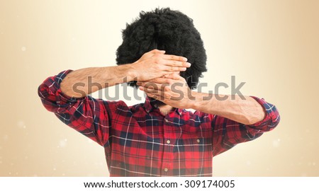 Afro man covering his face over ocher background