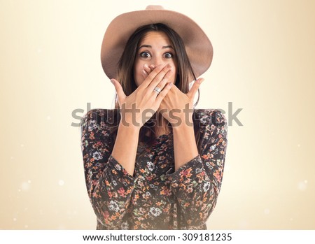 Woman covering her mouth over ocher background
