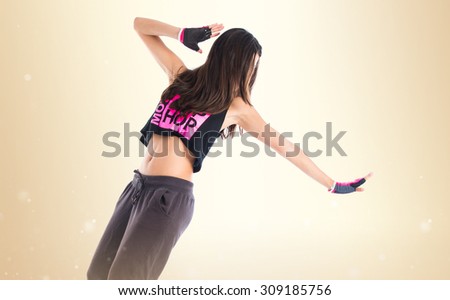 Teenager girl dancing street dance style over ocher background