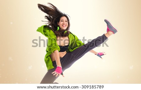 Teenager girl jumping in street dance style over ocher background