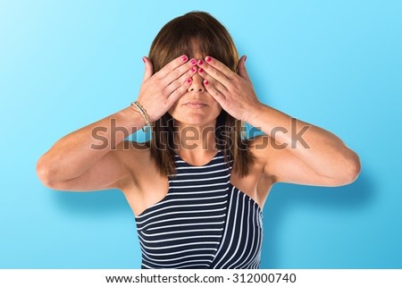 Woman covering her eyes over colorful background