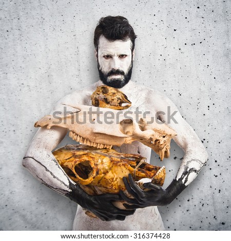 prehistoric man holding animal skulls over textured background