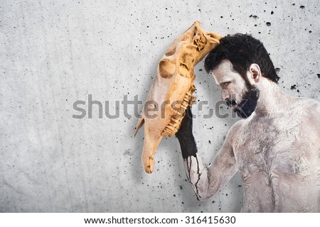 primitive man with horse skull like a mask on textured background