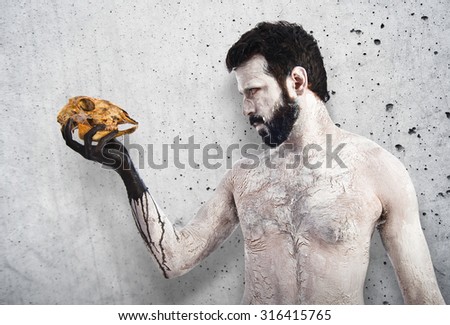 primitive man looking a rabbit skull on textured background