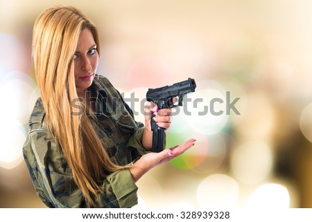 Military woman carrying a gun on unfocused background
