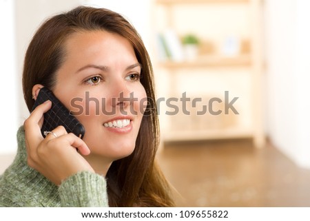 Beautiful white female at home wearing a green sweater with straight long brunette hair.