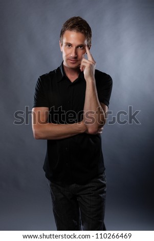Good looking Caucasian guy in studio on gray background wearing modern black shirt.