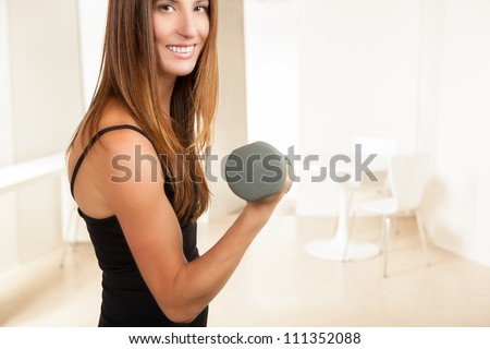 Beautiful young woman wearing black exercise clothes with grey weight working out.