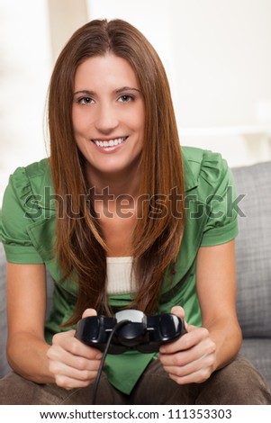 Attractive young woman relaxing at home playing a game holding controller sitting on couch.