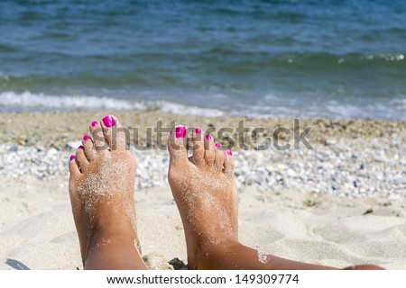 Woman sandy feet with nail polish on beach