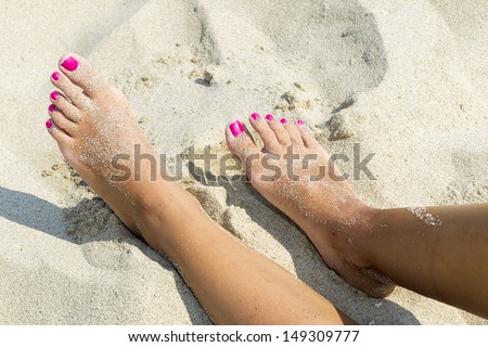Woman sandy feet with nail polish on beach
