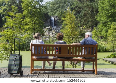 People sitting on a bench in a beautiful green city park in Grugapark Essen, Germany.