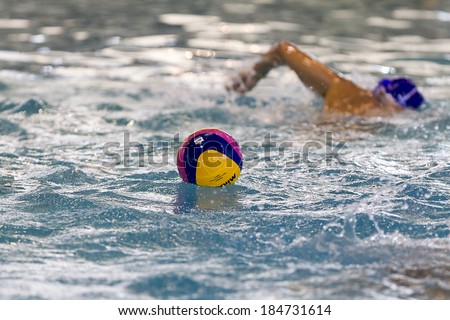 THESSALONIKI, GREECE MAR 22,2014:A water polo ball floating on the water in a pool and players in action in the background during the Greek League water polo game PAOK vs Vouliagmeni on March 22,2014