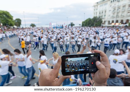 THESSALONIKI, GREECE- JUNE 1, 2014: Thessaloniki breaks the Guinness World Record with 1102 people dancing Rueda de casino, particular type of Salsa in Aristotelous square, Greece. Focus on phone