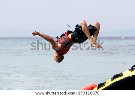 HALKIDIKI, GREECE- MAY 26, 2014: Unrecognized man doing back flip over water. 20 million tourists expected to visit the beaches, making it a record, in Halkidiki, Greece.