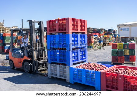NAOUSSA, GREECE- JULY 10, 2014: A worker transporting boxes with fruits of Agricultural Cooperative of Naoussa, Greece. The famous \