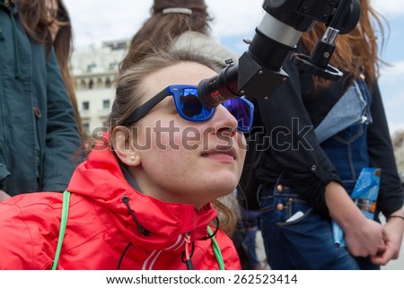THESSALONIKI, GREECE, MARCH 20, 2015: People watch through a telescope into the sky at a partial solar eclipse. Over Greece  the moon was scheduled to cover approximately 45%
