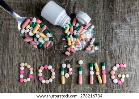 The word doping written with pills on a wooden background.