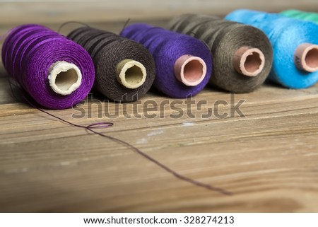Spools of thread on wooden background. Old sewing accessories. colored threads