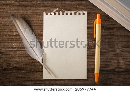 Still life with note and feather pen on wood background