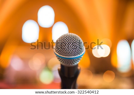 Microphone in concert hall or conference room with defocused bokeh lights in background
