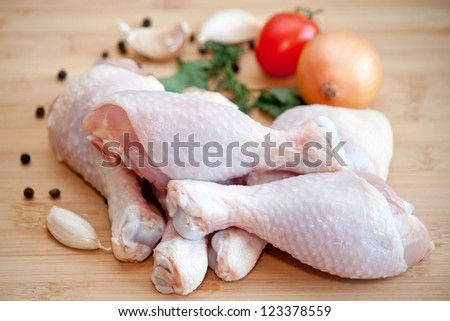 Raw chicken legs with vegetables and spices on the chopping board