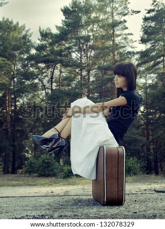 Sweet woman sit on a suitcase
