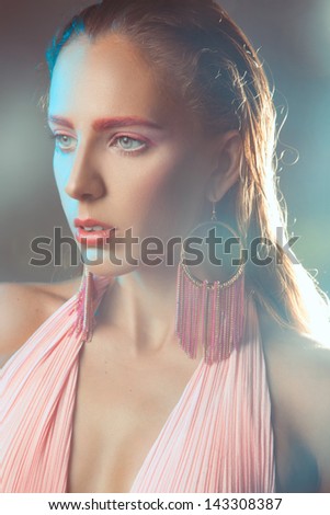 Portrait of woman with pink make up in haze in studio on gray background