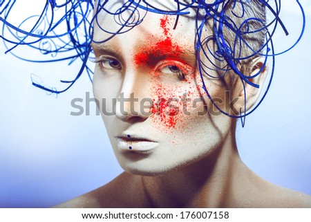 sexual woman with body art and neon powder in studio on blue background