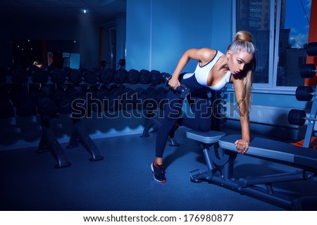 Fitness model doing exercises with dumbbell in gym