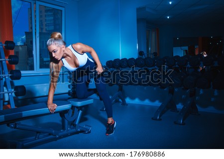 Attractive fitness model doing exercises with dumbbell in gym