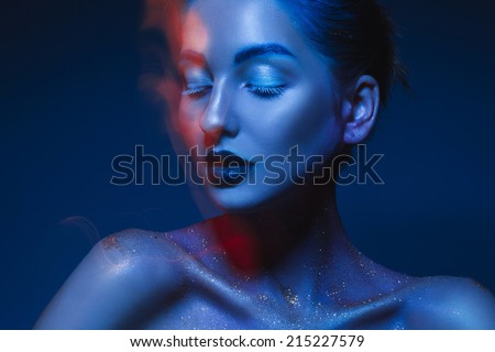 Horizontal portrait of sensual woman in blue body art in studio