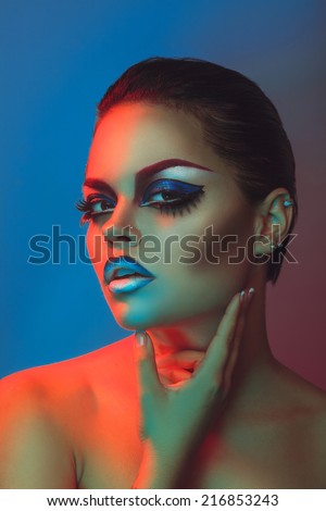 Beauty woman with make up and healthy skin in red and blue lights in studio