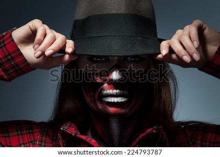 Horizontal portrait of female with scary face art for halloween night looking at camera in studio