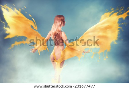 Young beautiful blonde with yellow wings on blue background with smoke in studio. Horizontal photo