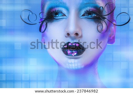 Wonderful portrait of beauty model looking away on blue background with creative face art. Studio shot