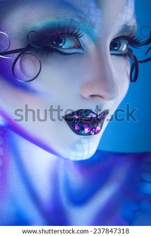 Lovely happy woman with creative face art looking at camera and smiling in studio